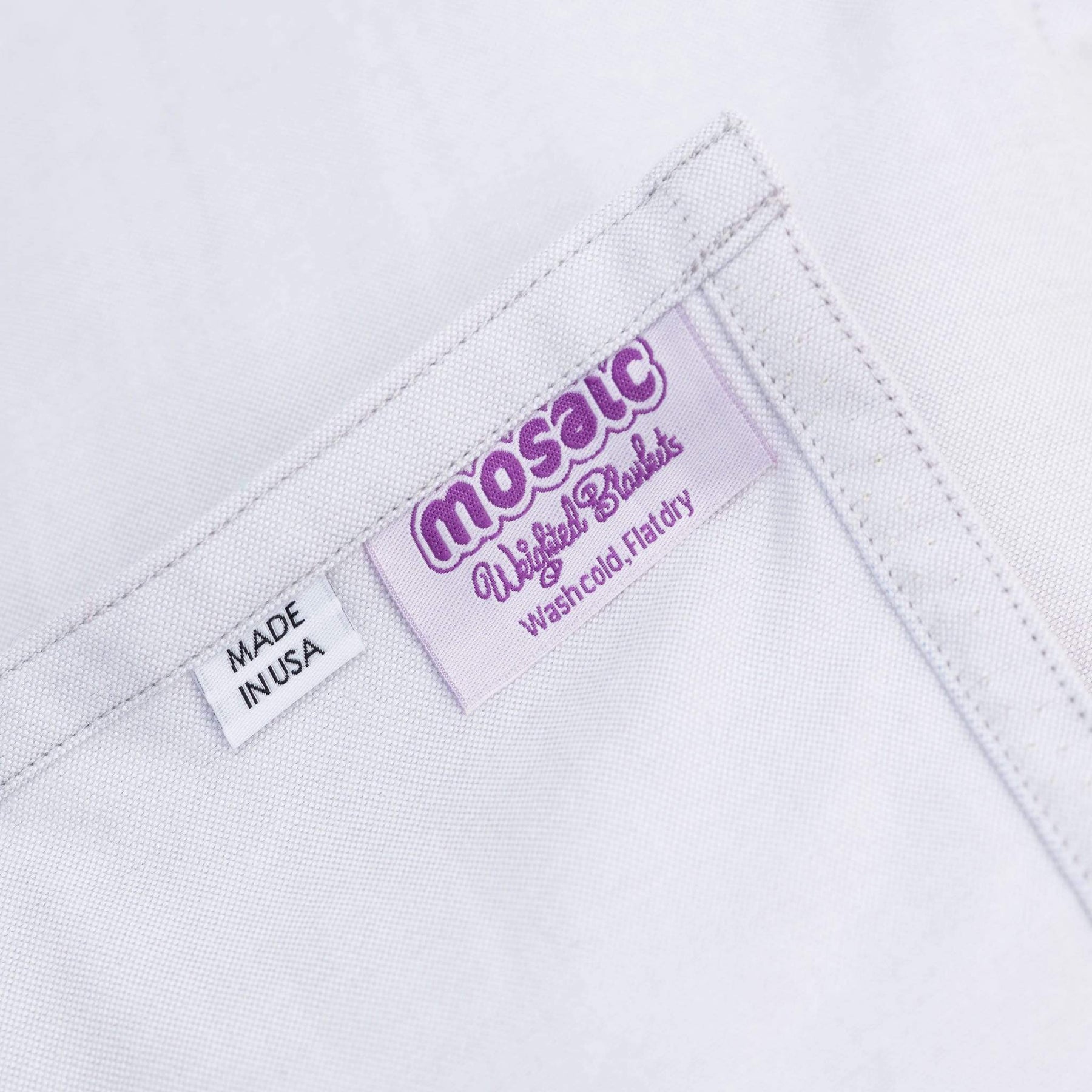 Close-up of the care label and stitched corner of a Mosaic weighted blanket